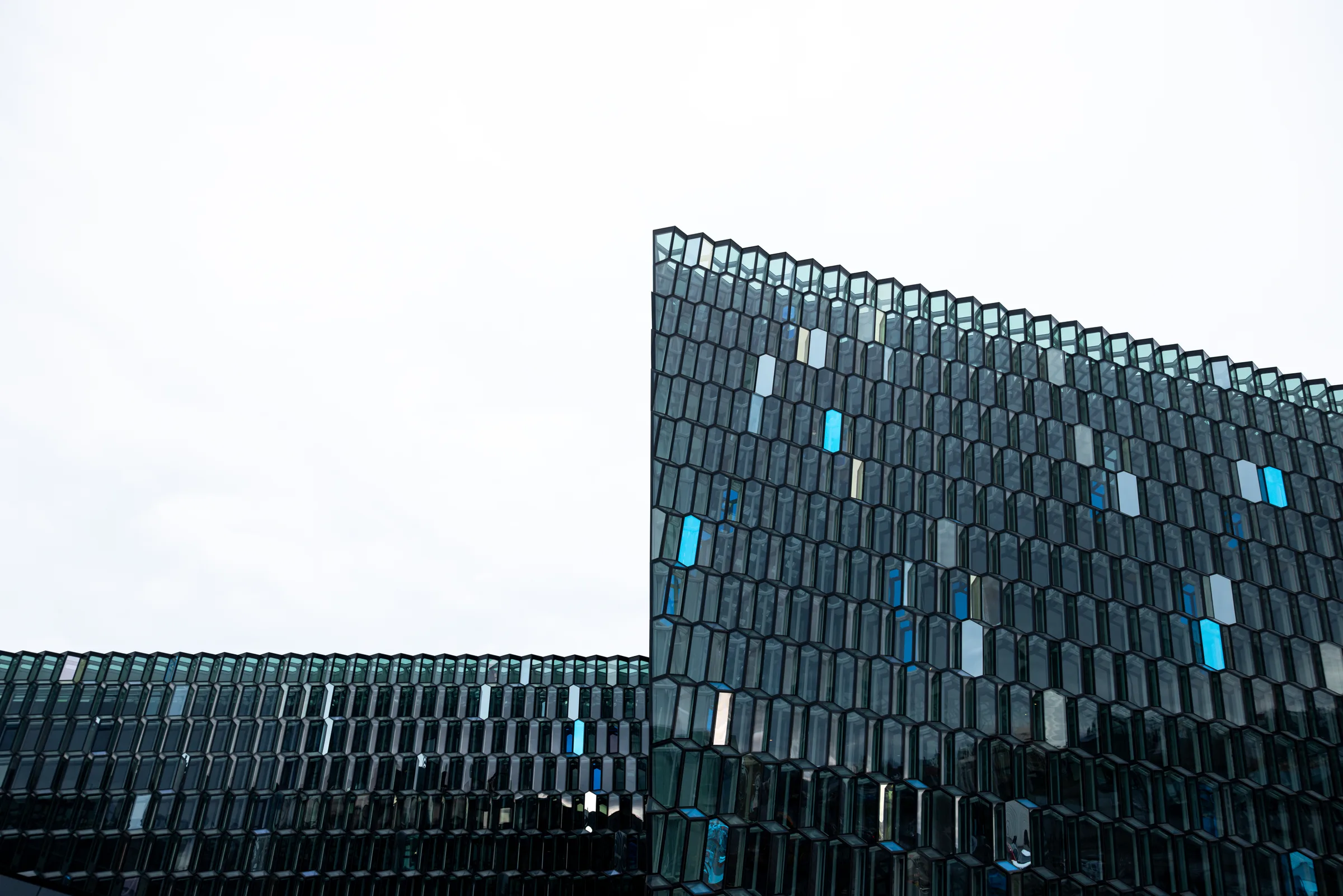 Harpa Concert Hall's honeycomb glass facade with scattered blue panels, Reykjavik, by ARCHTRAITS