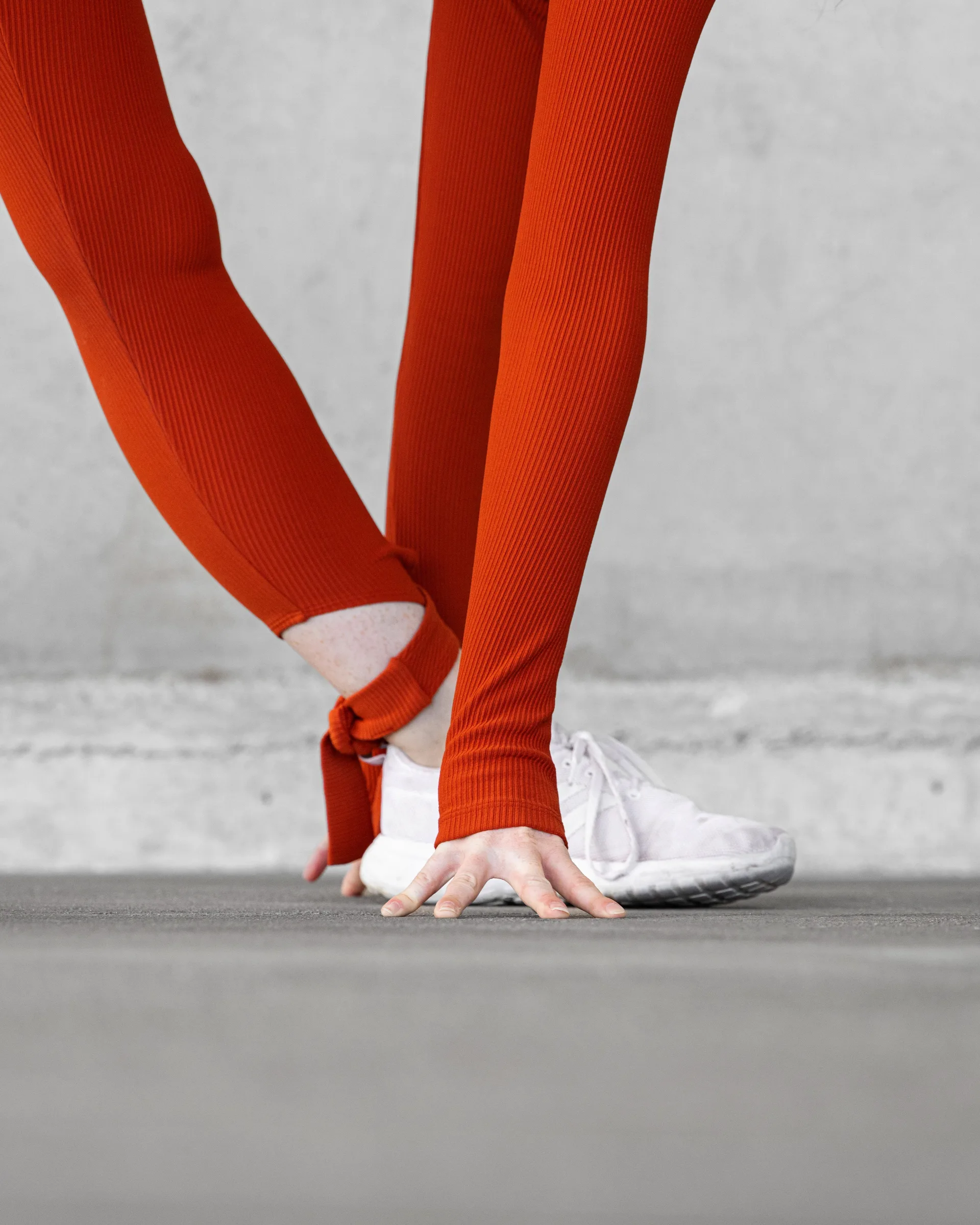 Close-up of a woman in red tying her shoelace while crouching at 1111 Lincoln Road, Miami Beach, by ARCHTRAITS