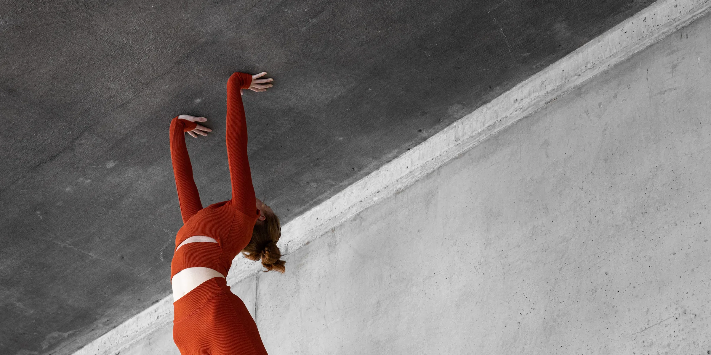 Woman in red in a low lunge with hands on the ground, looking up, at 1111 Lincoln Road, Miami Beach, by ARCHTRAITS
