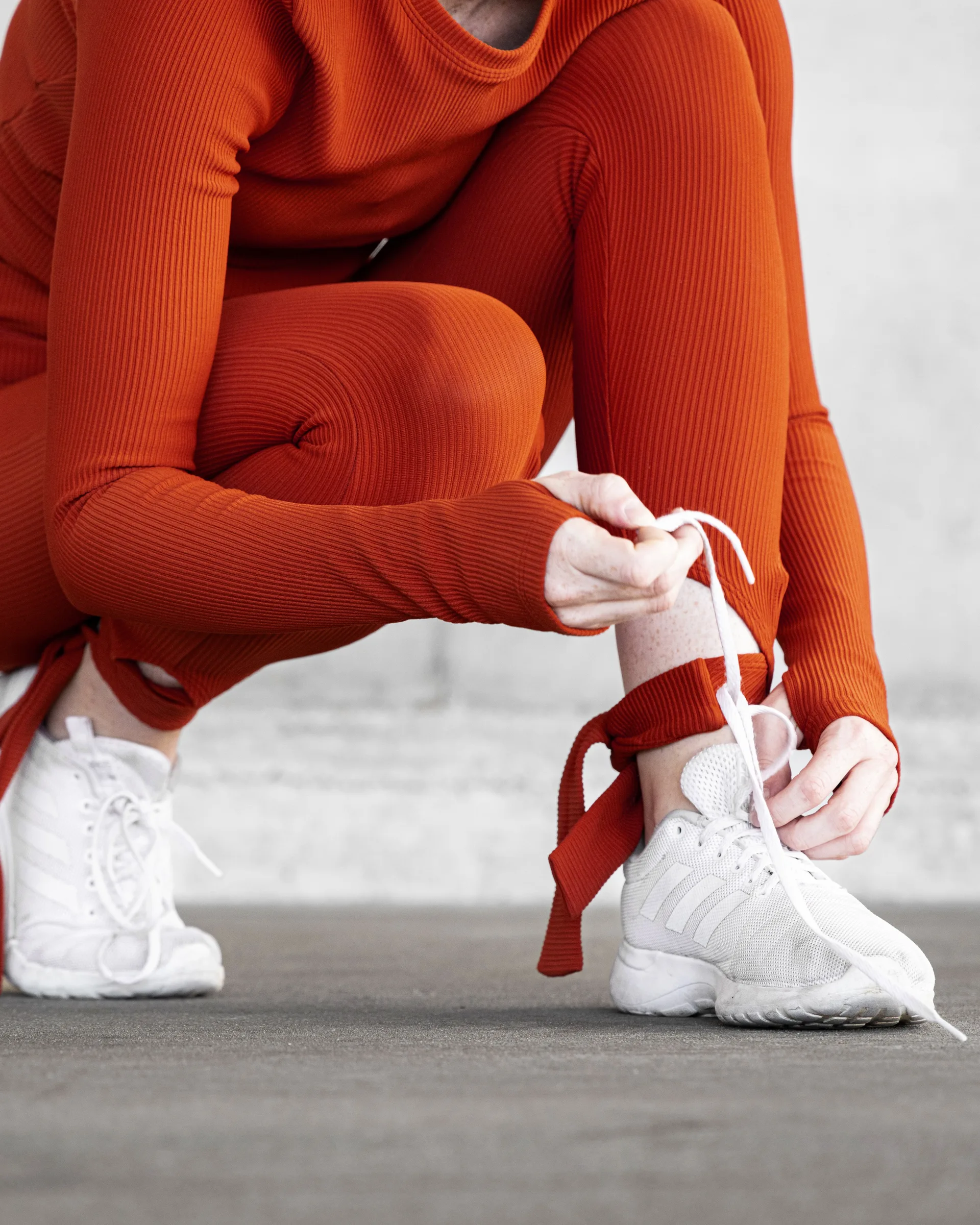 Close crop of a woman in red crouching to tie her shoelace at 1111 Lincoln Road, Miami Beach, by ARCHTRAITS