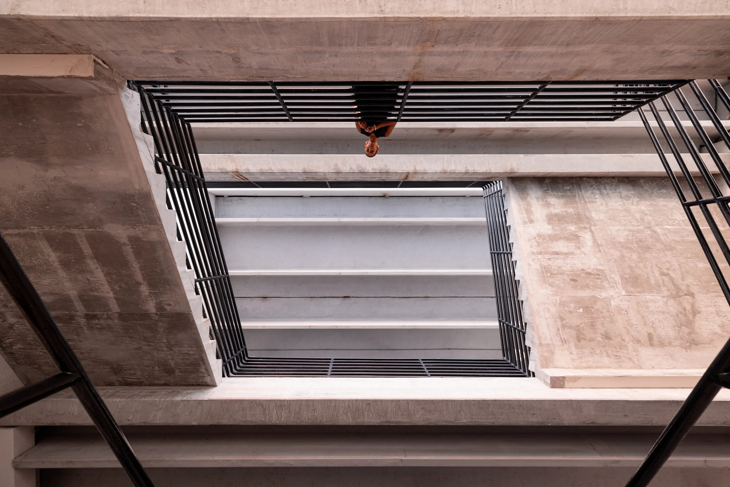 Aerial view up a square concrete stairwell with a woman standing at the top, FIU School of Architecture, Miami, by ARCHTRAITS