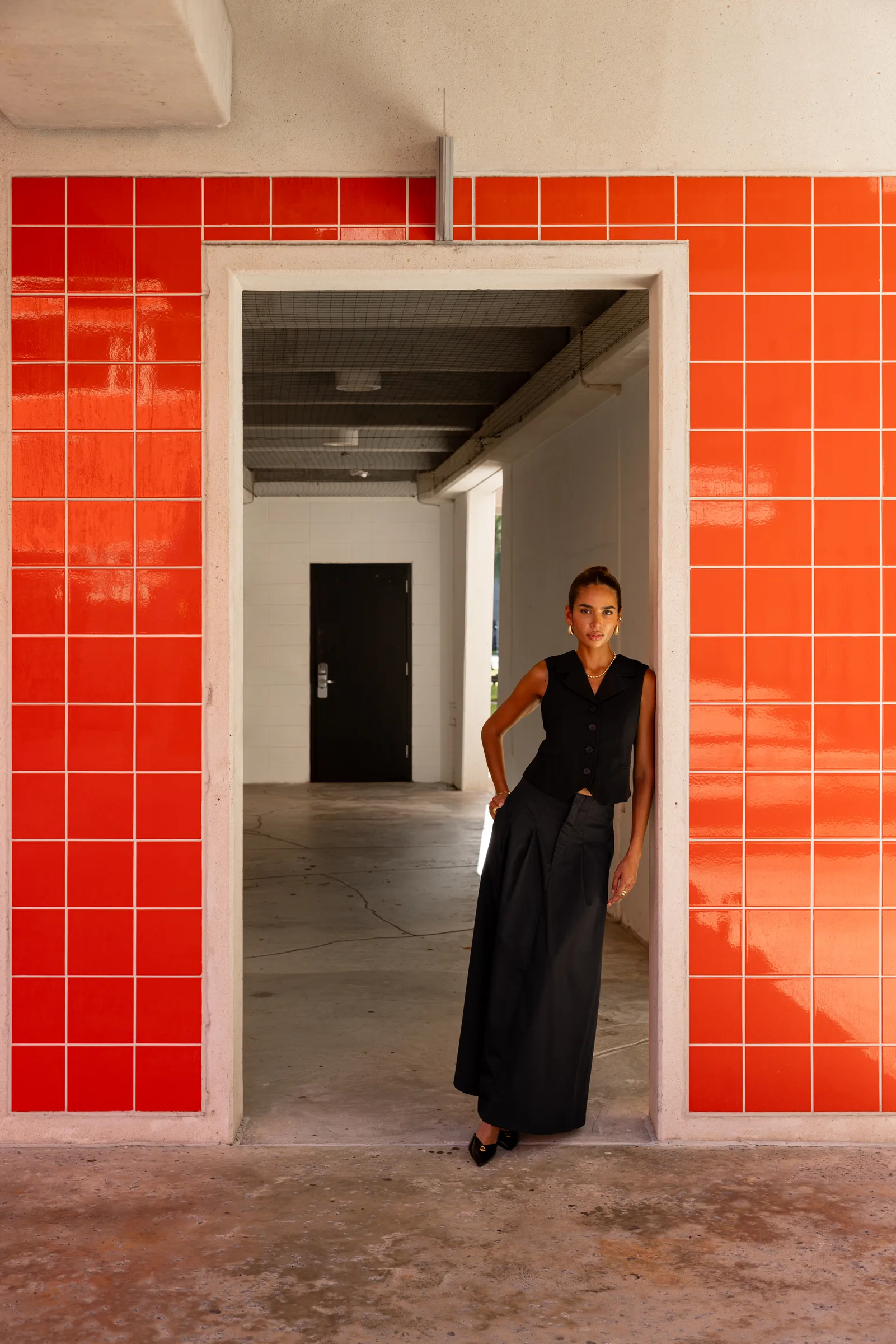 Woman standing in an orange-tiled doorway opening at FIU School of Architecture, Miami, by ARCHTRAITS