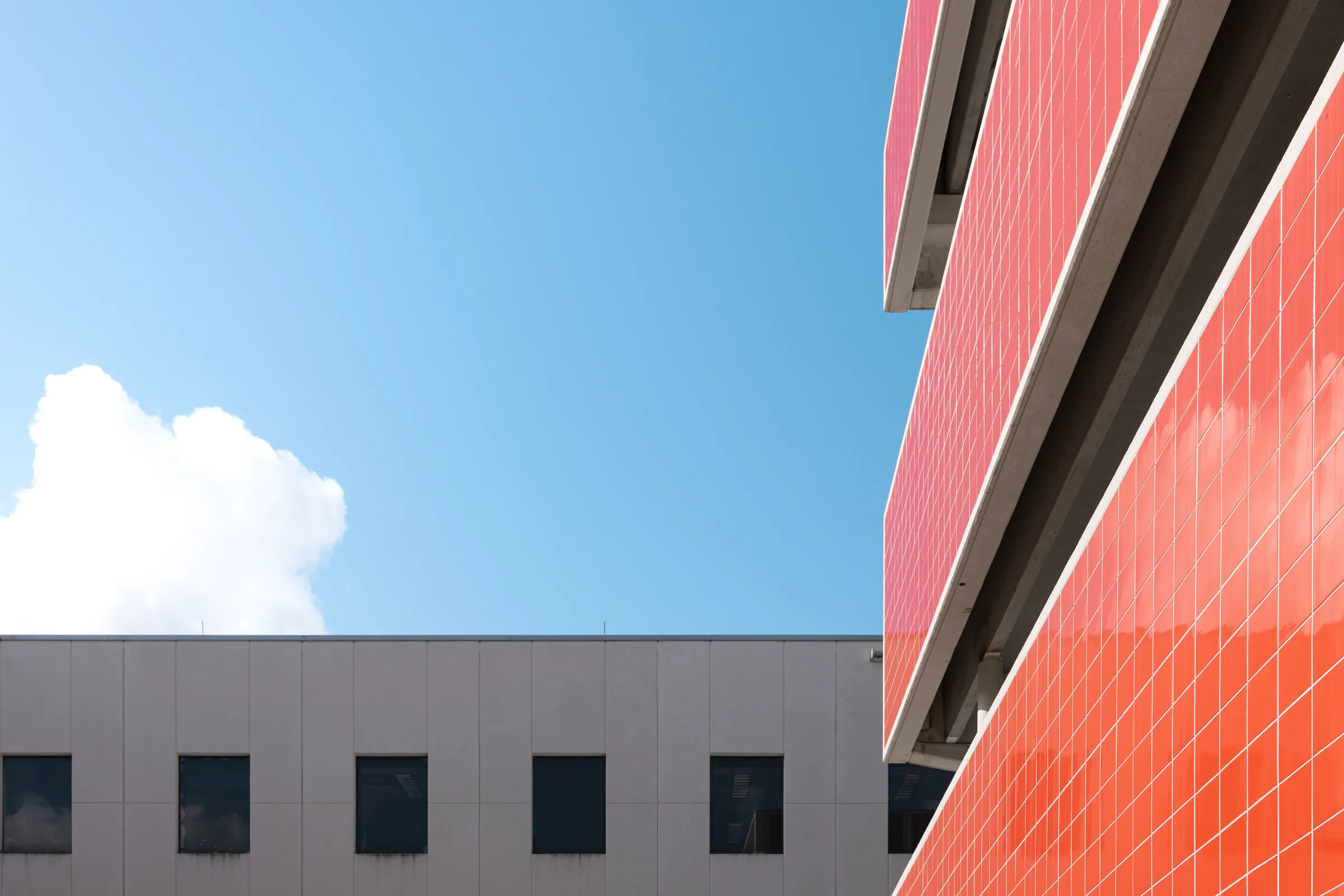 Detail of a red-and-orange tiled corner against a blue sky with a cloud, FIU School of Architecture, Miami, by ARCHTRAITS