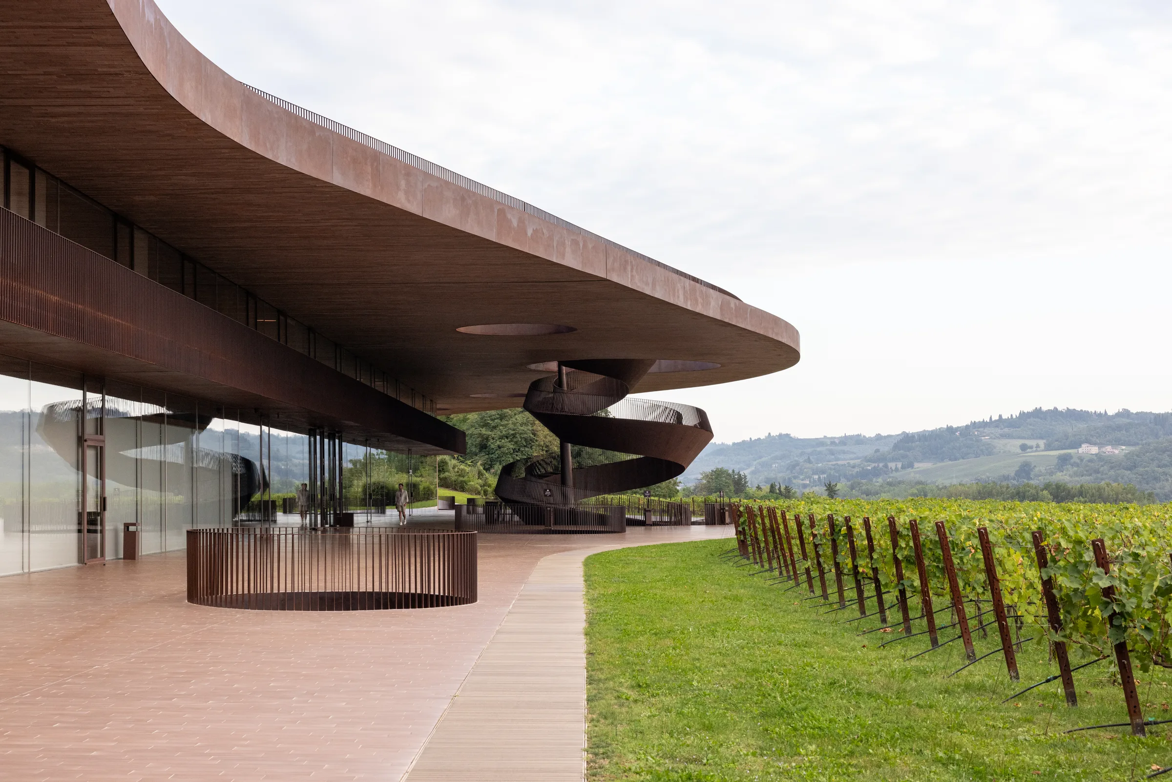 Cantina Antinori's sweeping roofline and spiral staircase rising above the vineyard at dusk, Tuscany, by ARCHTRAITS