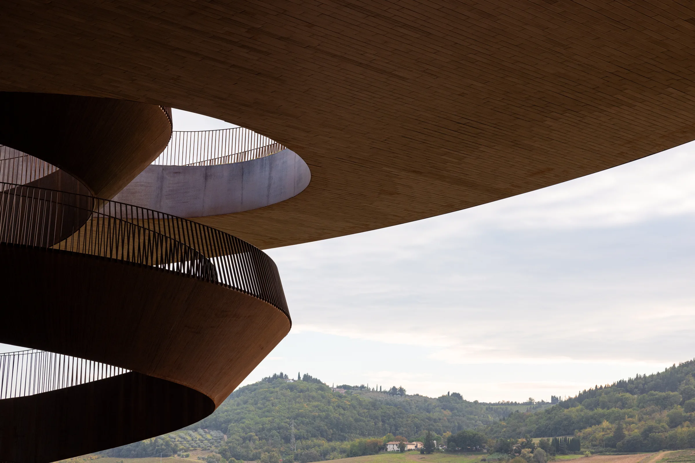 Detail of Cantina Antinori's spiral staircase and cantilevered roof against the Tuscan hills, by ARCHTRAITS