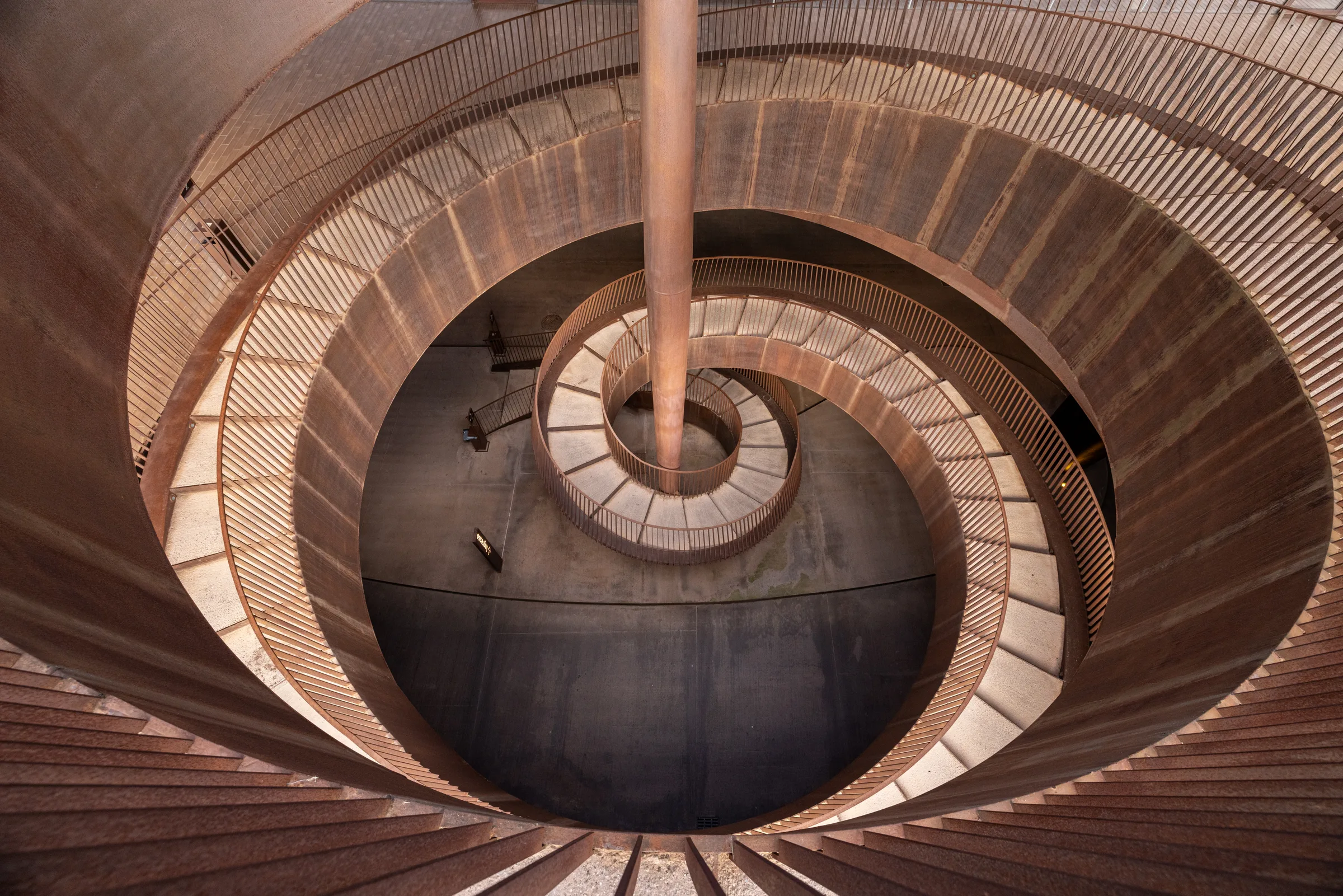 Aerial view down the center of Cantina Antinori's spiraling corten steel staircase, Tuscany, by ARCHTRAITS