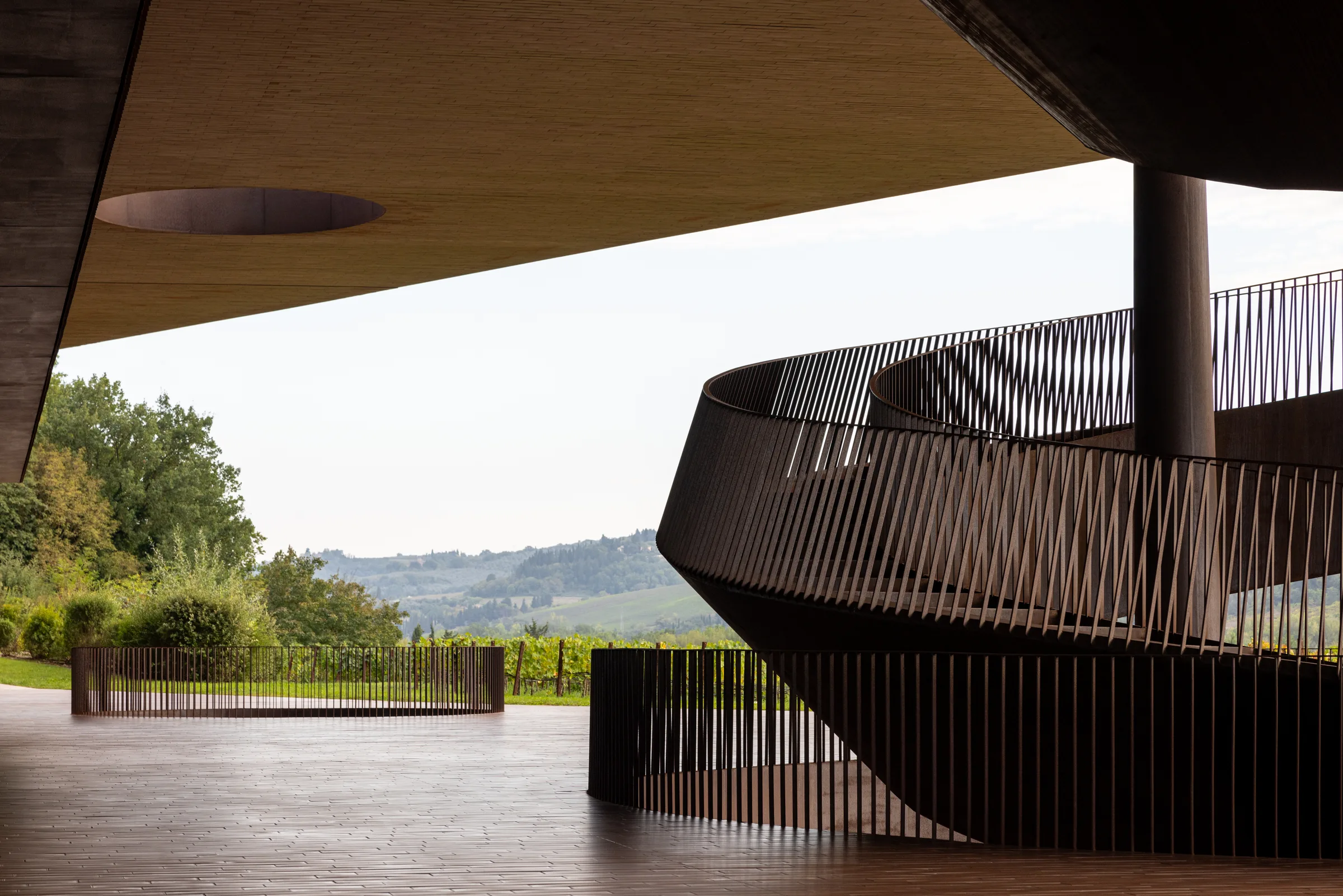 Cantina Antinori's spiraling corten steel staircase beneath its cantilevered roof, overlooking the Tuscan hills, by ARCHTRAITS