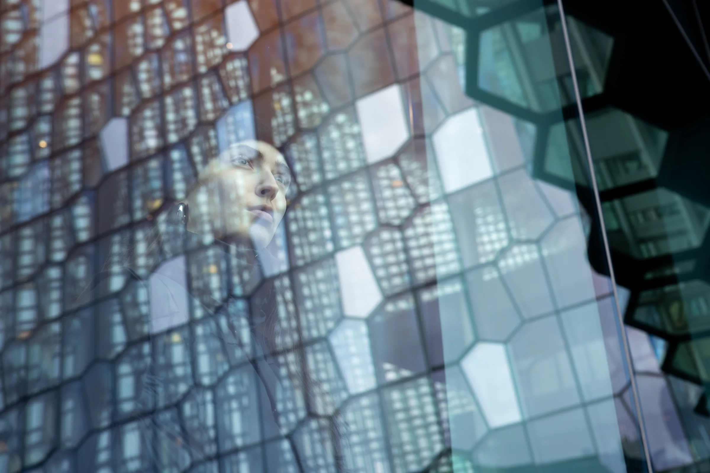 Woman's face reflected within Harpa Concert Hall's honeycomb glass facade, Reykjavik, by ARCHTRAITS