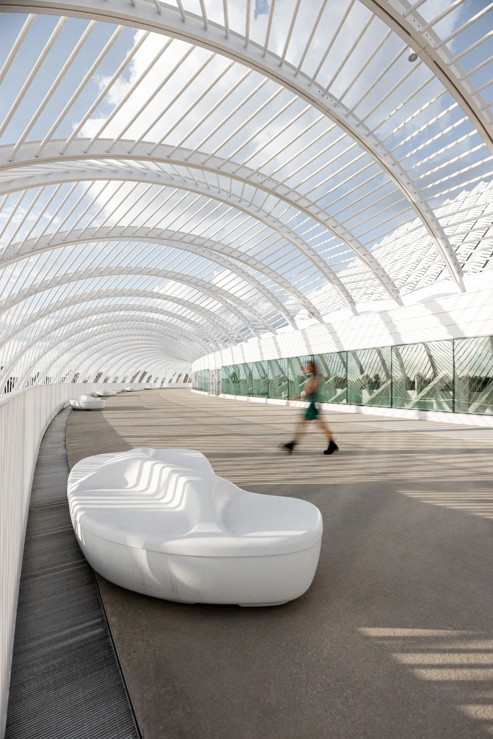 Person walking beneath the Innovation, Science, and Technology Building's curved white ribbed canopy walkway, Miami, by ARCHTRAITS
