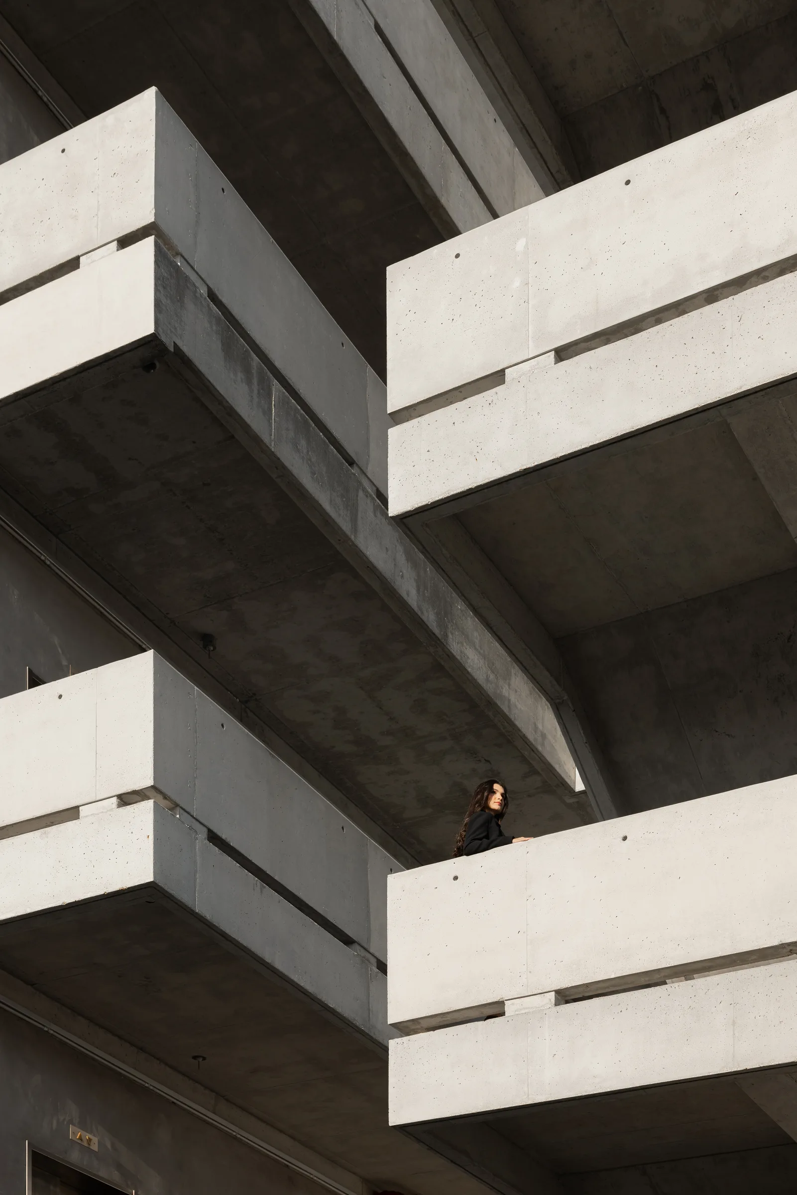 Dramatic concrete cantilevered balconies at Miami Dade College with a woman standing on the lower balcony, Florida, by ARCHTRAITS