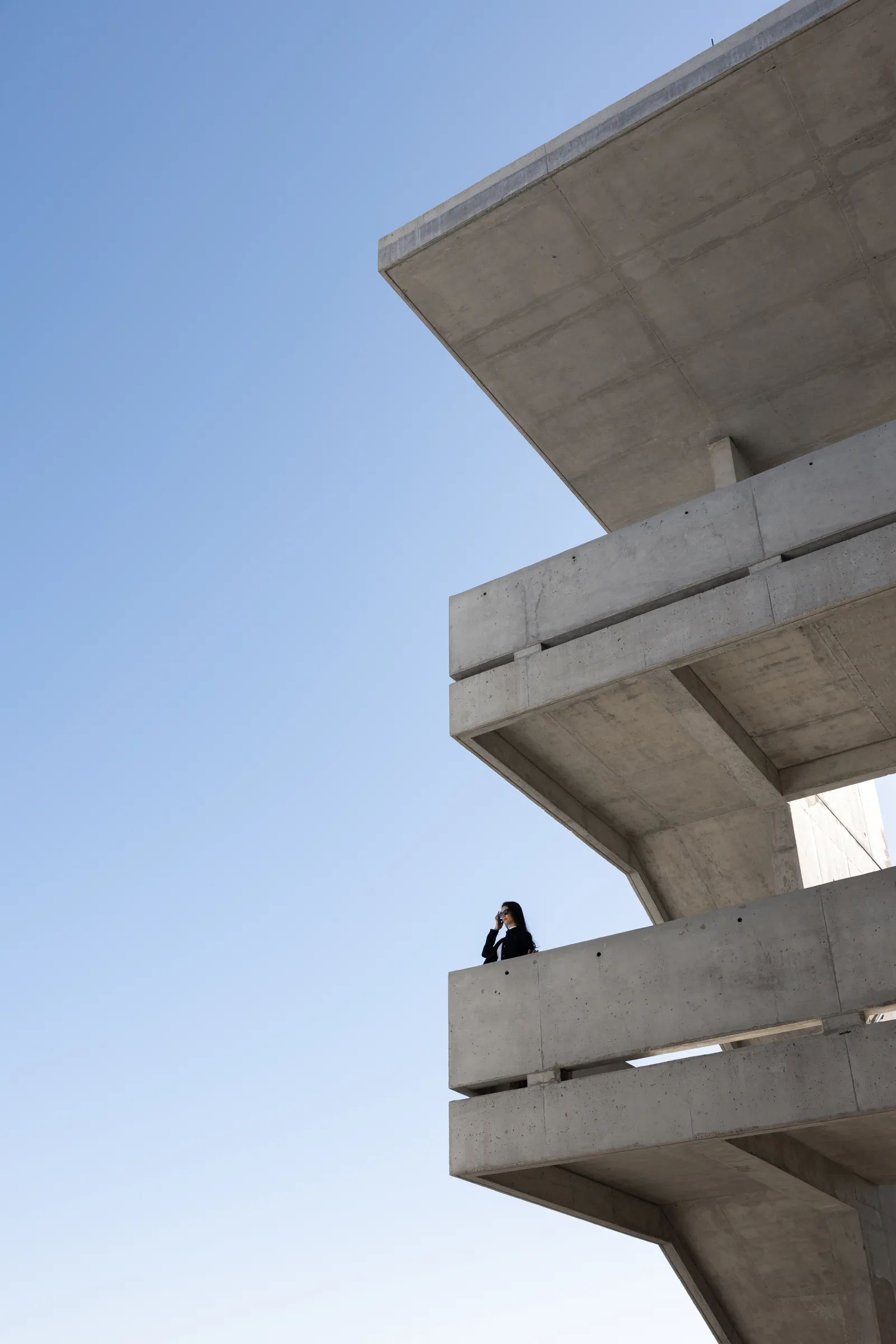 Close portrait of a woman leaning on a diagonal concrete railing in dramatic sunlight at Miami Dade College, Florida, by ARCHTRAITS