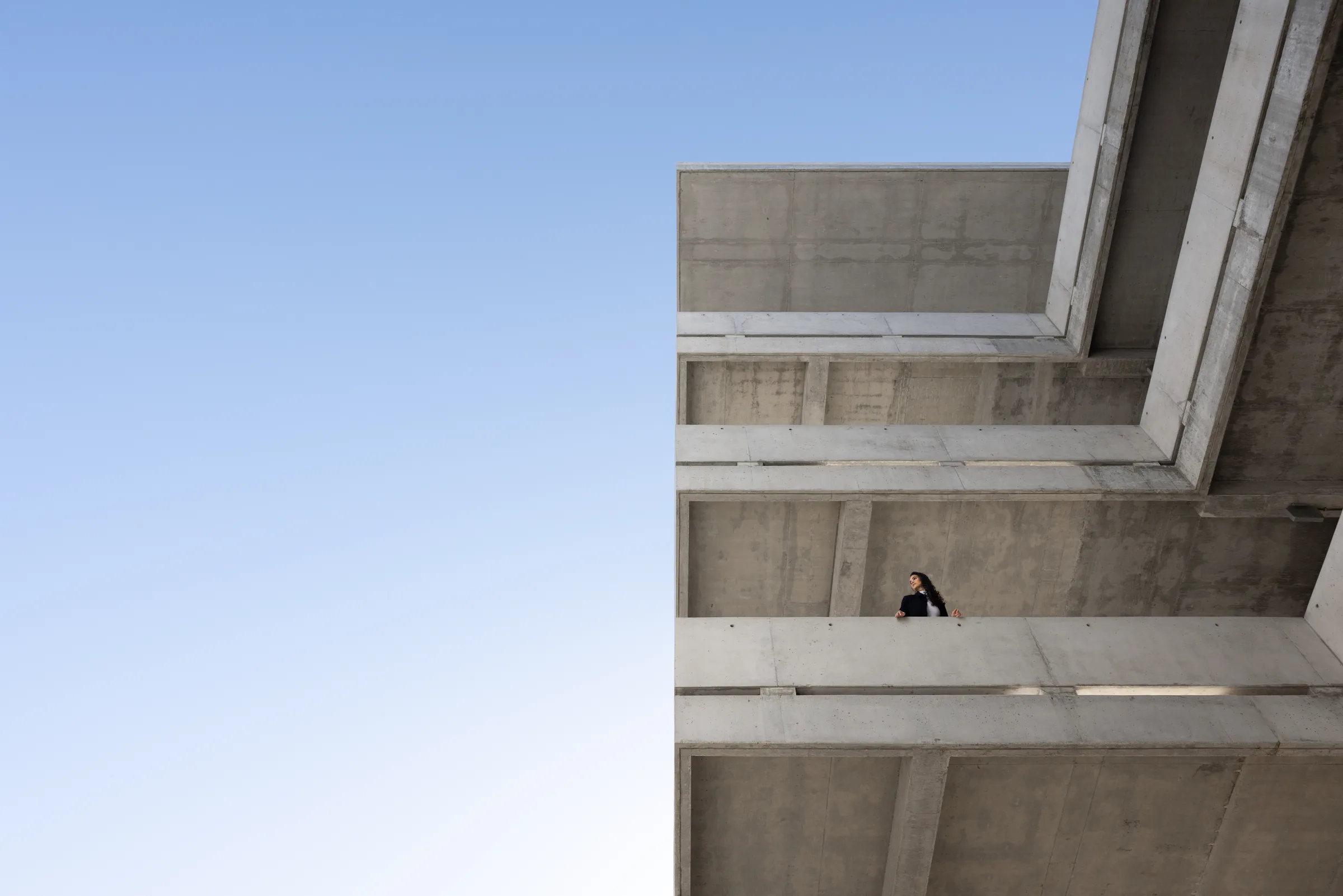 Wide view of cantilevered concrete balconies with a woman standing small amid the dramatic architecture, Miami Dade College, Florida, by ARCHTRAITS